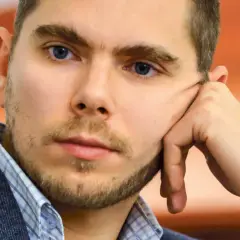 Portret Piotra Zychowicza, mężczyzny z niebieskimi oczami, opierającego głowę na dłoni.